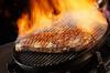 Sirloin steak amidst flames on a table grill